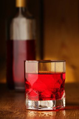 a glass full of colored vodka on a background of wooden boards