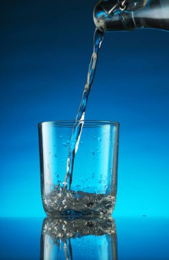 pouring water into a glass on a blue background