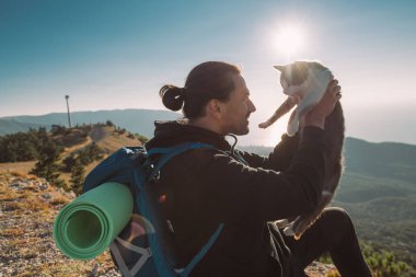 Bir erkek turist dağlarda şafakla tanışır. Yürüyüş. Genç yakışıklı bir adam sabah dağın tepesine tırmandı ve arkadaşı kedisiyle birlikte bir uçurumun kenarında oturdu. Kedi şafak vakti bir adamla dağlarda gezer.
