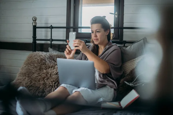 Mujer Trabaja Con Ordenador Portátil Teléfono Cama Dormitorio Una Joven —  Fotos de Stock