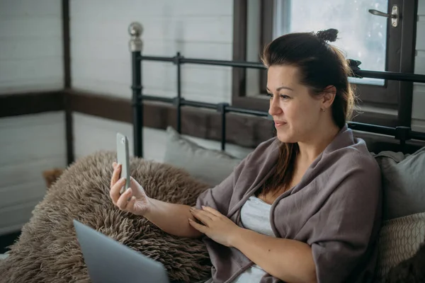 Mujer Trabaja Con Ordenador Portátil Teléfono Cama Dormitorio Una Joven —  Fotos de Stock