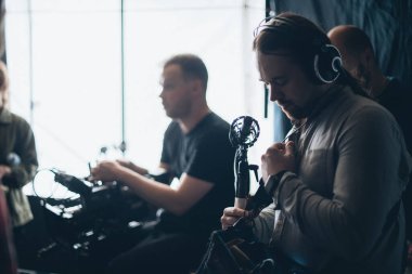 Sette mikrofonu olan ses mühendisi. Profesyonel bir ses mühendisi, bir film, ticari ya da televizyon dizisinin çekimlerinde çalışıyor. İçerideki çekim süreci, stüdyo.