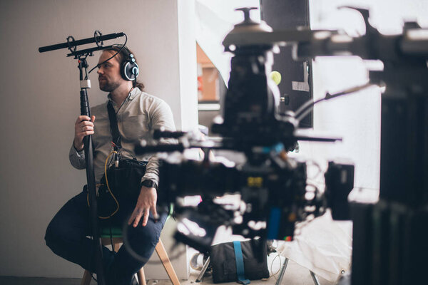 Sound engineer with a microphone on the set. A professional sound engineer at work on the filming of a movie, commercial or TV series. Filming process indoors, studio