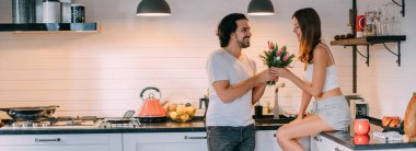 Uluslararası Kadınlar Günü. Sabahın köründe evdeki mutfakta genç bir çift. Bir erkek, 8 Mart 'ta bir kadına şık bir mutfakta bir buket lale verir..