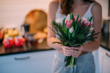 Bir kadının ellerinde bir buket çiçek. Uluslararası Kadınlar Günü. Genç bir kız lalelerin elinde topallıyor..