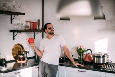 Yüzünde yamalar olan bir adam dinleniyor. Erkeklerin kişisel bakımı. Genç yakışıklı adam yüzüne bakar, mutfakta çay içer..