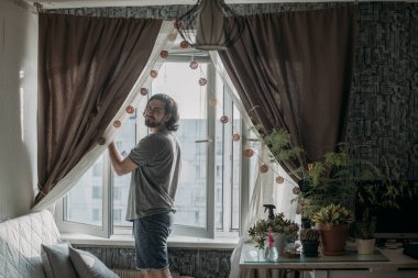 Evdeki pencereleri temizleyen bir adam. Genç yakışıklı adam sıcak bir dairede bahar temizliği yapıyor..