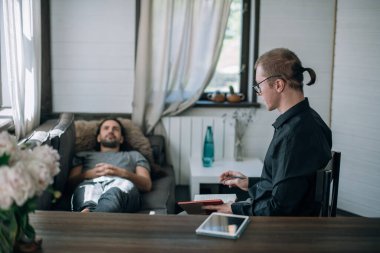 Psikoterapist ve hasta ofiste bir randevuda. Genç doktor müşterinin sözlerini bir deftere yazar. Bir erkek hasta, büyük, parlak bir ofiste, bir kanepede yatıyor.