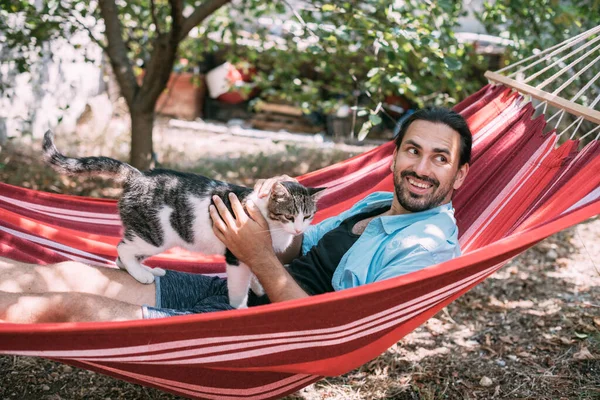 Joven Está Descansando Acariciando Gato Una Hamaca Jardín Chico Guapo —  Fotos de Stock