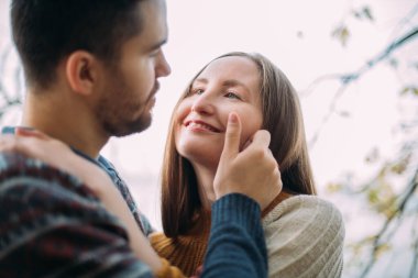 Sevgili bir çiftin randevudaki portresi. Yakın plan. Genç yakışıklı bir adam kız arkadaşına sarılıyor, yüzünü okşuyor, onu öpüyor..