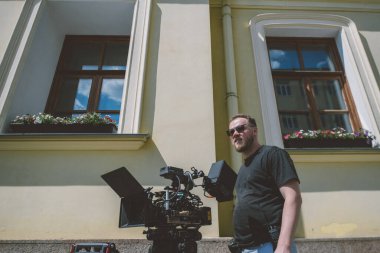 Görüntü yönetmeni elinde kamerayla sette. Bir film, ticari ya da televizyon dizisi çekmek için çalışan profesyonel bir videograf. Sokakta, konumda çekim işlemi.