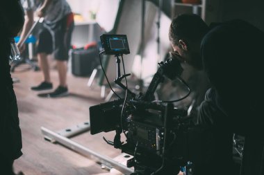 Görüntü yönetmeni elinde kamerayla sette. Bir film, ticari ya da televizyon dizisi çekmek için çalışan profesyonel bir videograf. İçerideki çekim süreci, stüdyo.