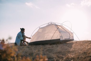 Genç erkek turist dağlara çadır kurdu. Adam yürüyüş için kamp kurmuş, gün batımında dağlarda tek başına çadır kurmuş.
