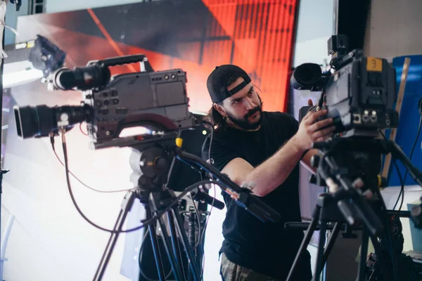 Director of photography with a camera in his hands on the set. Professional videographer at work on filming a movie, commercial or TV series. Filming process indoors, studio