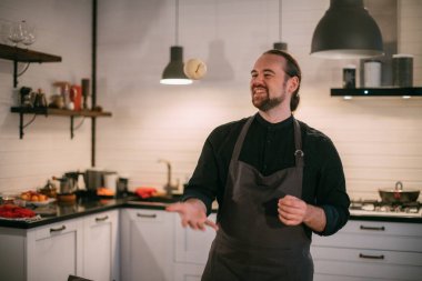 Erkek bir şef evde mutfakta hamur hazırlar. Evdeki mutfaktaki önlüklü genç adam. İçinde ev yapımı erişteler var.