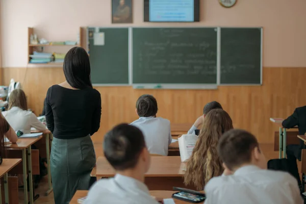 교사는 학교에서 교훈을 가르치고 칠판을 사용하여 교실에서 강의를 여자가 아이들에게 — 스톡 사진