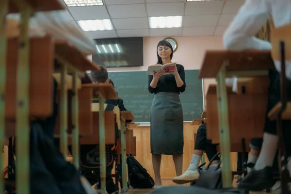 교사는 학교에서 교훈을 가르치고 칠판을 사용하여 교실에서 강의를 여자가 아이들에게 — 스톡 사진
