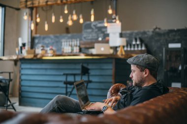 Dizüstü bilgisayarı olan bir adam kanepede çalışıyor. Genç ve şık bir adam bilgisayarın başında tek başına oturur ve kapalı bir yerde, birlikte çalışırlar. Yakın plan..
