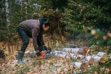 Bir adam elektrikli testereyle ağaç kesiyor. Genç bir adam çam ormanında çalışıyor, kış için odun topluyor. Bir oduncu ağaçların arasında testereyle bir sandık kesiyor..
