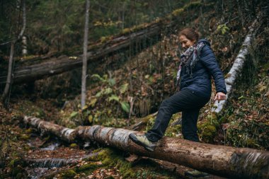 Sağlıklı bir emeklilik hayatı. Ormandaki yaşlı bir kadının portresi. Sonbahar ormanında yürüyüş yapan neşeli, güzel, emekli kadın..