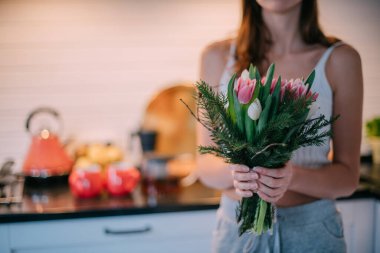 Bir kadının ellerinde bir buket çiçek. Uluslararası Kadınlar Günü. Genç bir kız lalelerin elinde topallıyor..