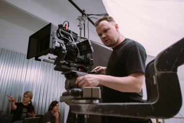 Görüntü yönetmeni elinde kamerayla sette. Bir film, ticari ya da televizyon dizisi çekmek için çalışan profesyonel bir videograf. İçerideki çekim süreci, stüdyo.