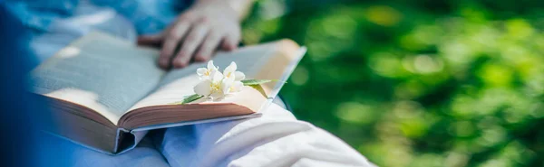 A man is resting and reading in a hammock. Close-up. Day off and relaxation. A young guy lies in a hammock with a book near a country house in the shade on a sunny day