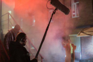 Sette mikrofonu olan ses mühendisi. Profesyonel bir ses mühendisi, bir film, ticari ya da televizyon dizisinin çekimlerinde çalışıyor. İçerideki çekim süreci, stüdyo.