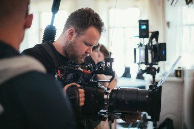 Görüntü yönetmeni elinde kamerayla sette. Bir film, ticari ya da televizyon dizisi çekmek için çalışan profesyonel bir videograf. İçerideki çekim süreci, stüdyo.