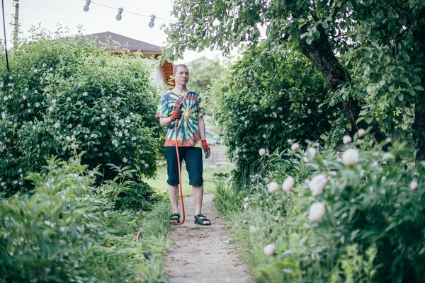 Uomo Sta Annaffiando Giardino Con Tubo Giovane Ragazzo Abiti Luminosi — Foto Stock