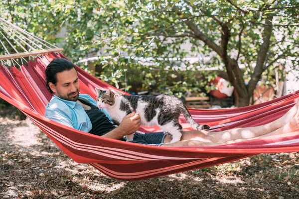 Joven Está Descansando Acariciando Gato Una Hamaca Jardín Chico Guapo —  Fotos de Stock