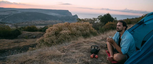 Genç Bir Erkek Turist Dağlarda Bir Çadırın Yanında Çay Içer — Stok fotoğraf