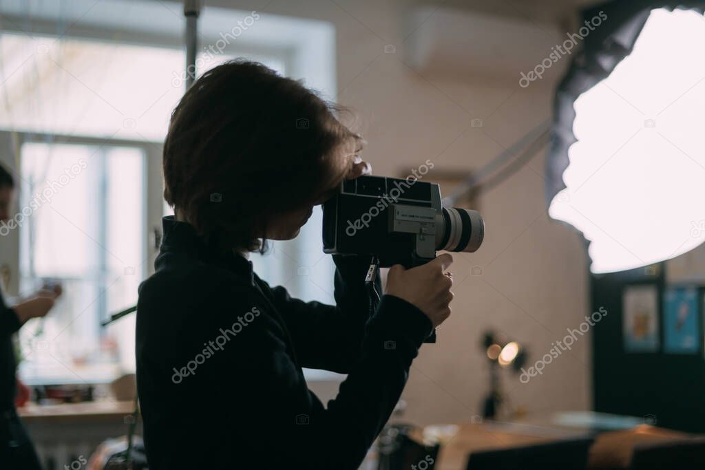 Female director of photography with a film camera on the shooting. Modern filming process of a film, advertising on the set.