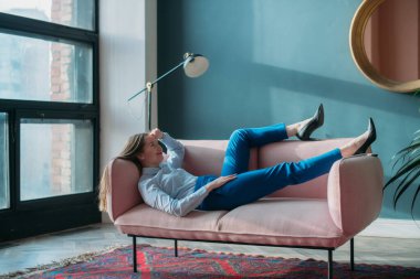 Modern ofis içinde kanepenin üzerinde kavramsal iş kadını portresi. Takım elbiseli şık bir genç kız kanepede yatıyor. İş kadını, bir iş kadını portresi..