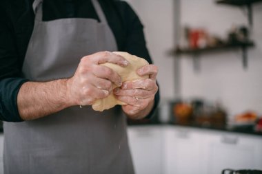 Erkek bir şef mutfakta erişte hamuru hazırlar. Un ve hamurla ellerini kapat. Mutfağındaki önlüklü genç adam masanda erişte pişirmek için malzemelerle bekliyor.
