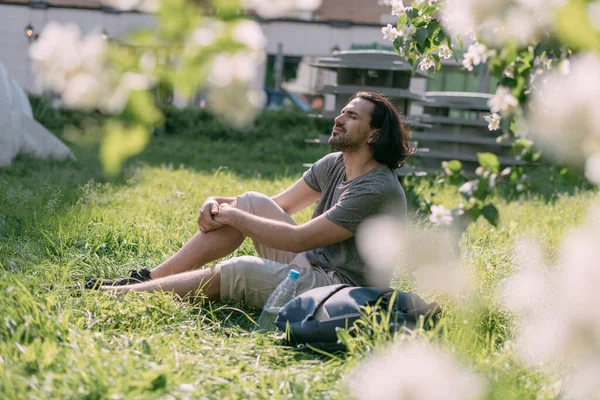 Een Man Zit Het Gras Een Bloeiend Park Een Grote — Stockfoto