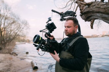 Görüntü yönetmeni elinde kamerayla sette. Bir film, ticari ya da televizyon dizisi çekmek için çalışan profesyonel bir videograf. Sokakta, konumda çekim işlemi.