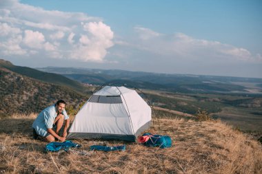 Genç erkek turist dağlara çadır kurdu. Adam yürüyüş için kamp kurmuş, gün batımında dağlarda tek başına çadır kurmuş.