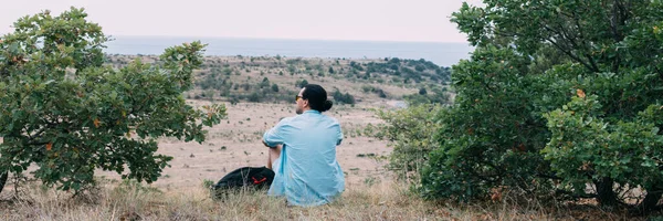 Turista Masculino Con Una Mochila Sienta Cima Colina Joven Está —  Fotos de Stock