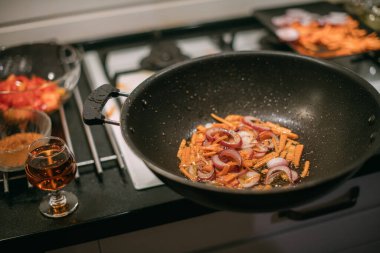 Sebzeli kızartma tavası ve yakın plan et. Erkek aşçı, mutfaktaki gaz ocağında büyük bir tavada yahni hazırlıyor.