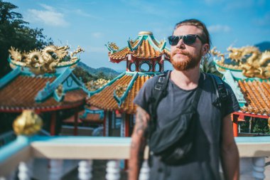 Tayland 'da bir dağ tapınağına gezintiye çıkan bir turist. Genç adam dağ yamacındaki küçük bir ada tapınağını ziyaret ediyor. Manzara ve ulusal mimariyi.