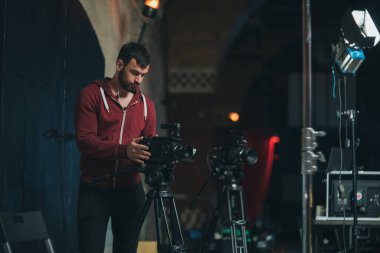 Görüntü yönetmeni elinde kamerayla sette. Bir film, ticari ya da televizyon dizisi çekmek için çalışan profesyonel bir videograf. İçerideki çekim süreci, stüdyo.