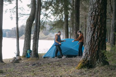 Evli bir çift gölün kıyısında bir turist kampını yıkıyor. Ormanda şenlik ateşiyle yürüyüş kampı. Erkek ve kadın birlikte bir çadır kurdular.