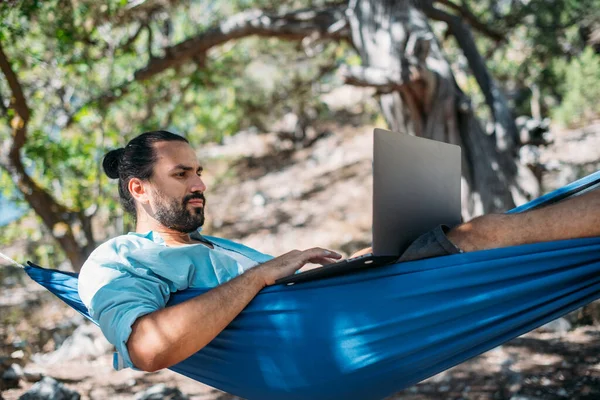 Een Man Werkt Een Laptop Terwijl Hij Een Hangmat Ligt — Stockfoto