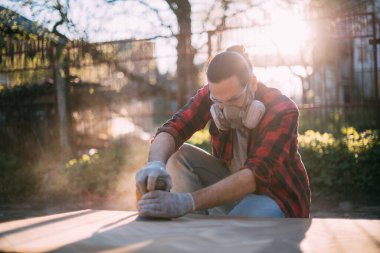 Erkek bir marangoz odun öğütücüsüyle çalışır. Profesyonel ekipmanlar ve koruyucu ekipmanlar. Genç profesyonel zımpara ahşap masa..