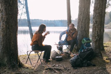 Evli bir çift gölün kıyısında çadırlı şekerlemeleri kızartıyor. Ormanda şenlik ateşiyle yürüyüş kampı. Kadın ve erkek, ateşin yanında sıcak içeceklerle sessizliğin tadını çıkarırlar.