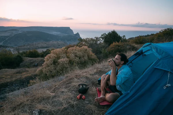 Genç Bir Erkek Turist Dağlarda Bir Çadırın Yanında Çay Içer — Stok fotoğraf