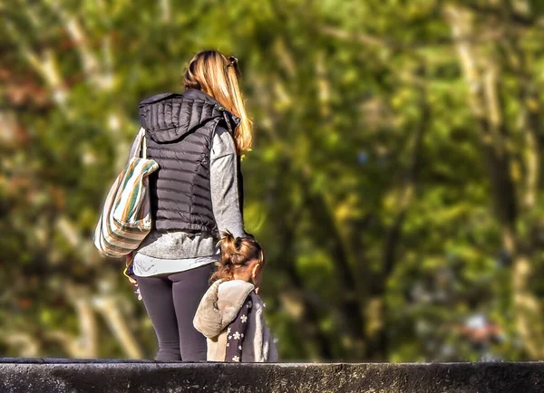 雨の後公園を歩いている彼女の小さな女の子とブロンドの髪の母親 — ストック写真