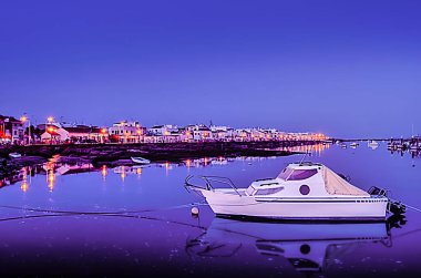 Kanalın suyunda yüzen teknelerle dolu gece manzarası.