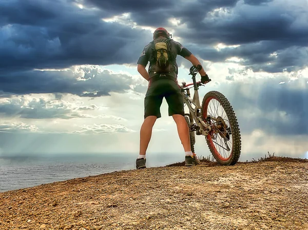 海の近くの丘の上の黒い歯車のサイクリスト — ストック写真